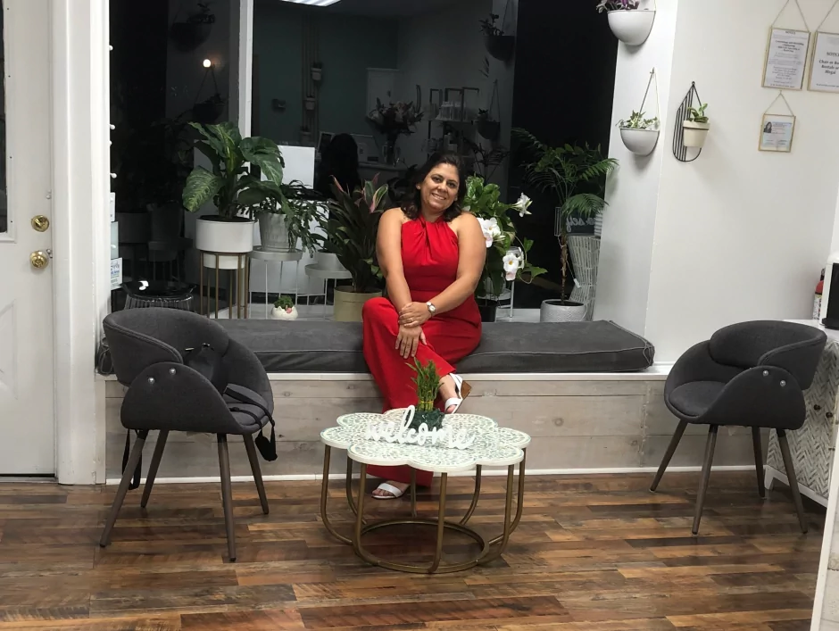 María F. Gómez sitting on a couch at Artistique Hair Studio opening